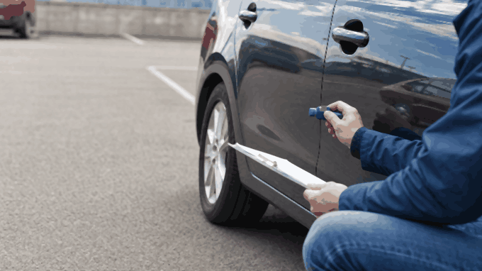 Appraiser measuring a car panel gap, the kind of check behind a diminished value estimate